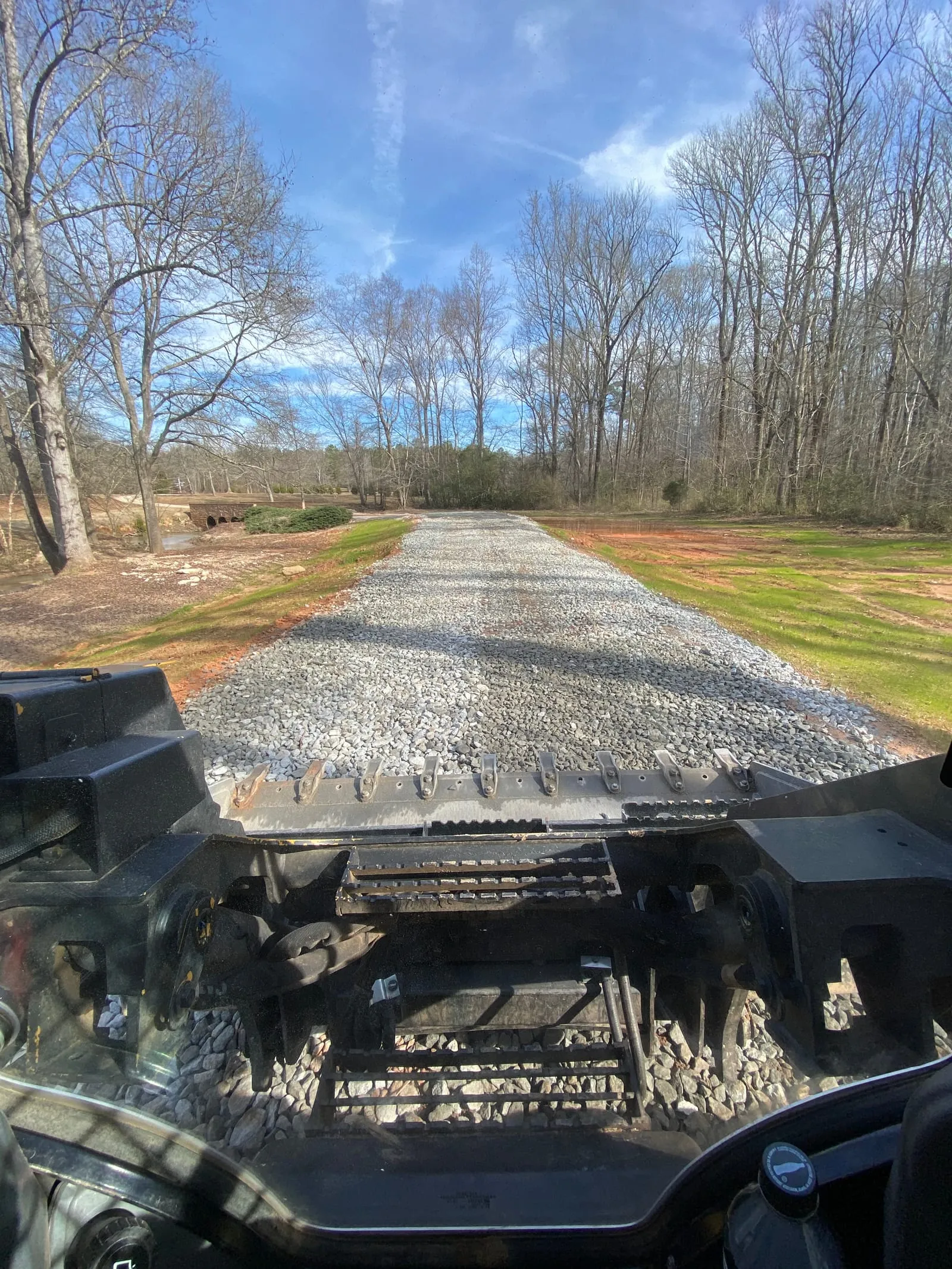 Freshly spread gravel driveway seen from the cab of a Ballard machine.
